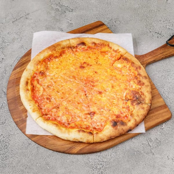 A whole cheese pizza on a wooden serving board, placed on a gray textured surface.